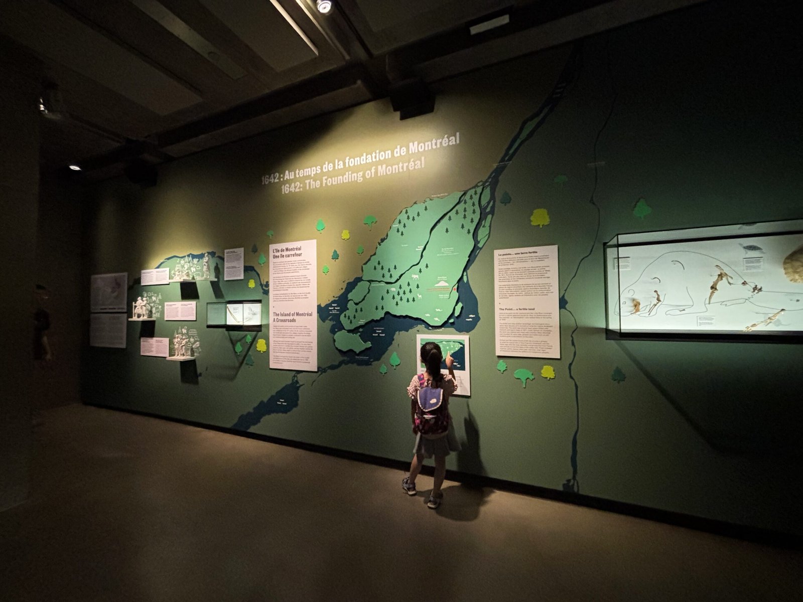 A child looks at an interactive wall exhibit about the founding of Montreal in 1642.