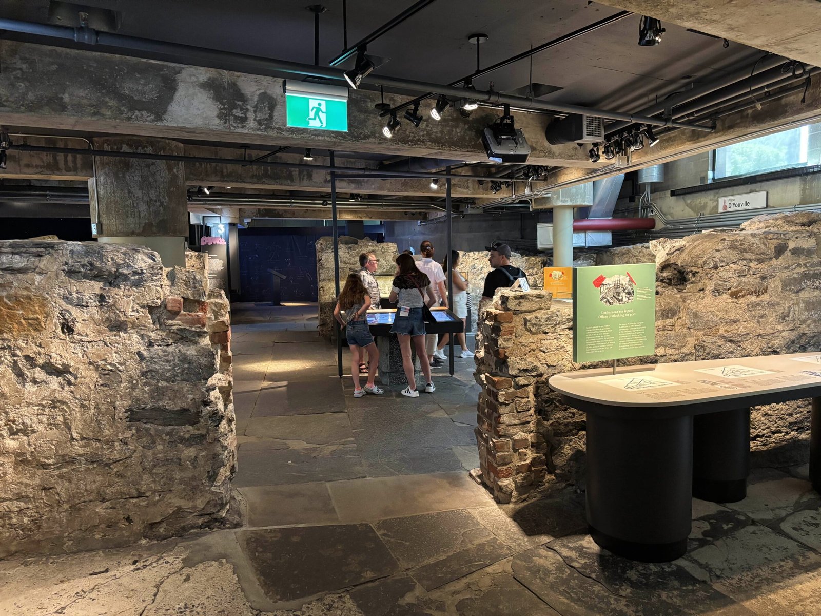 Visitors walking through ancient stone walls in Pointe-à-Callière’s underground archaeological site.