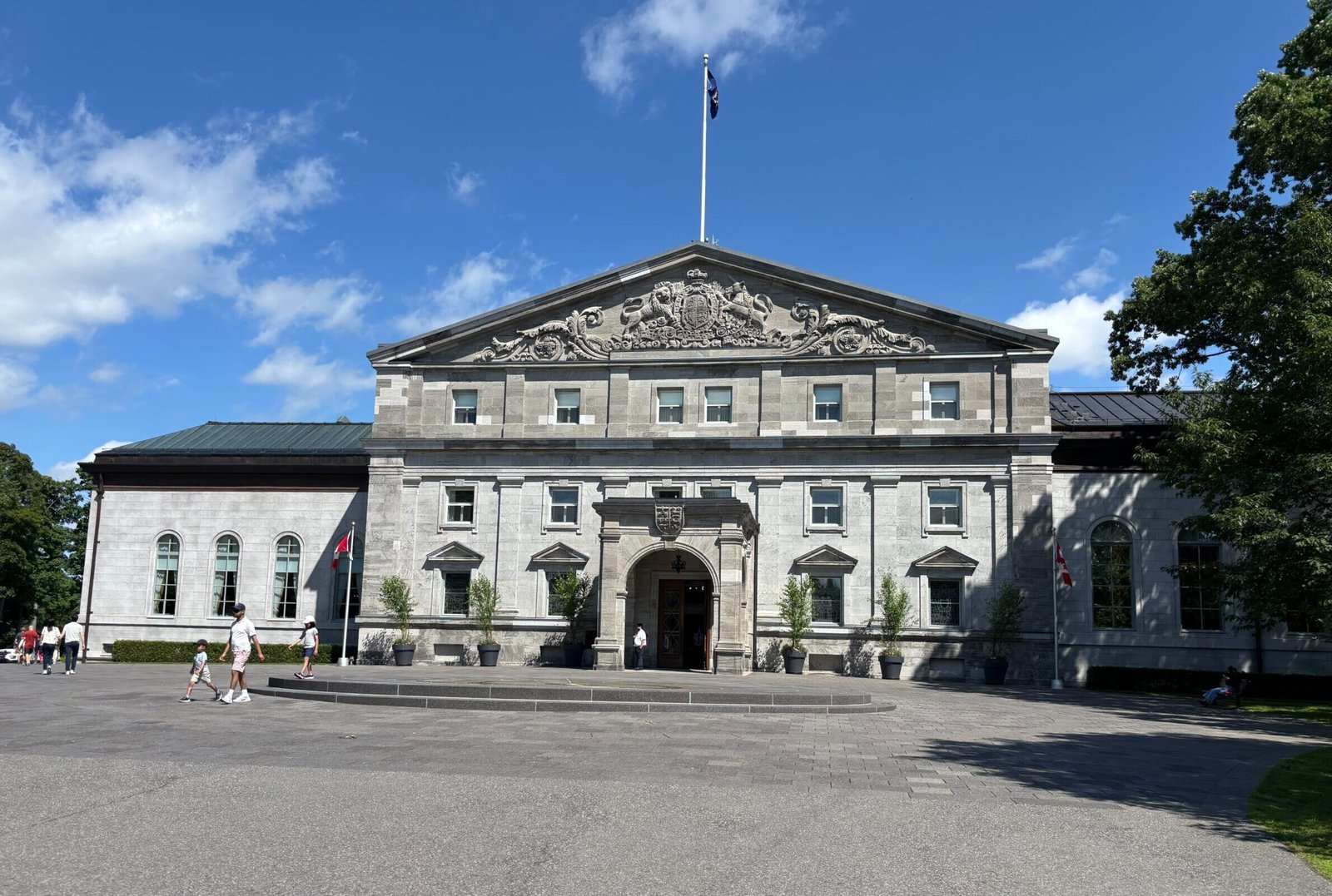 Front view of Rideau Hall’s main building with Canadian flags and visitors