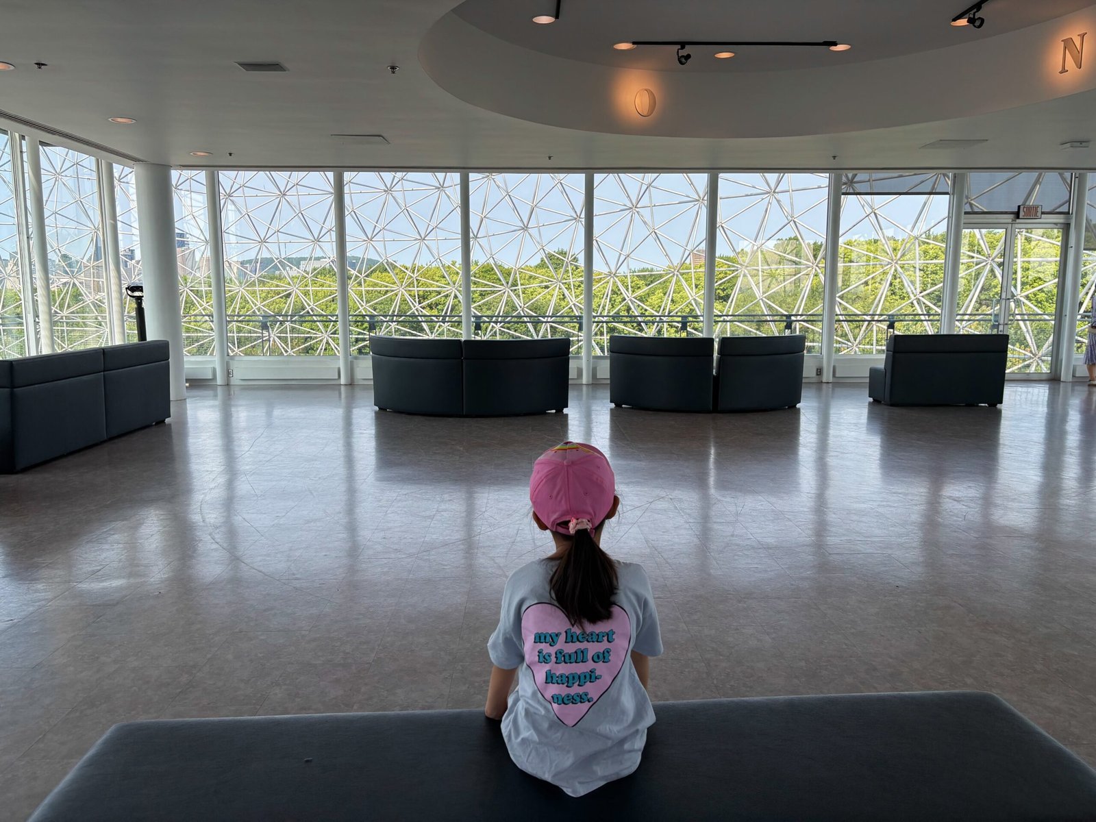 Child sitting inside the Biosphere dome overlooking Montreal’s greenery and skyline.