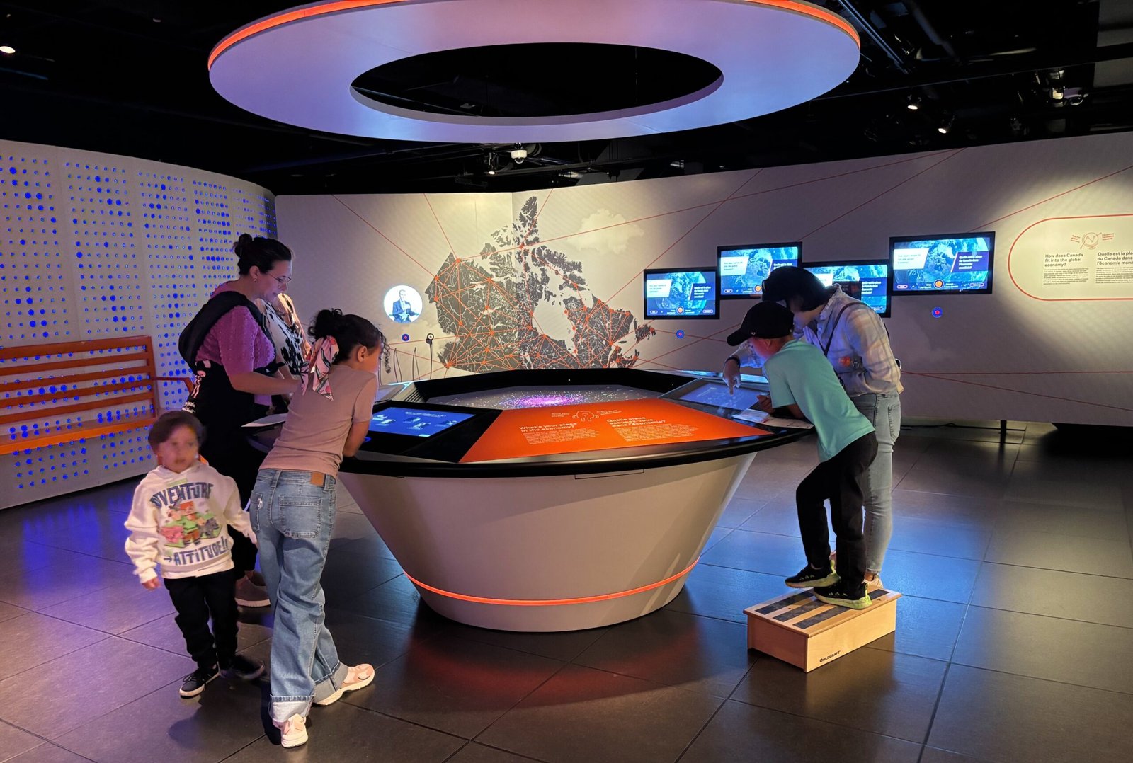 Visitors exploring an interactive touchscreen map of Canada inside the Bank of Canada Museum.