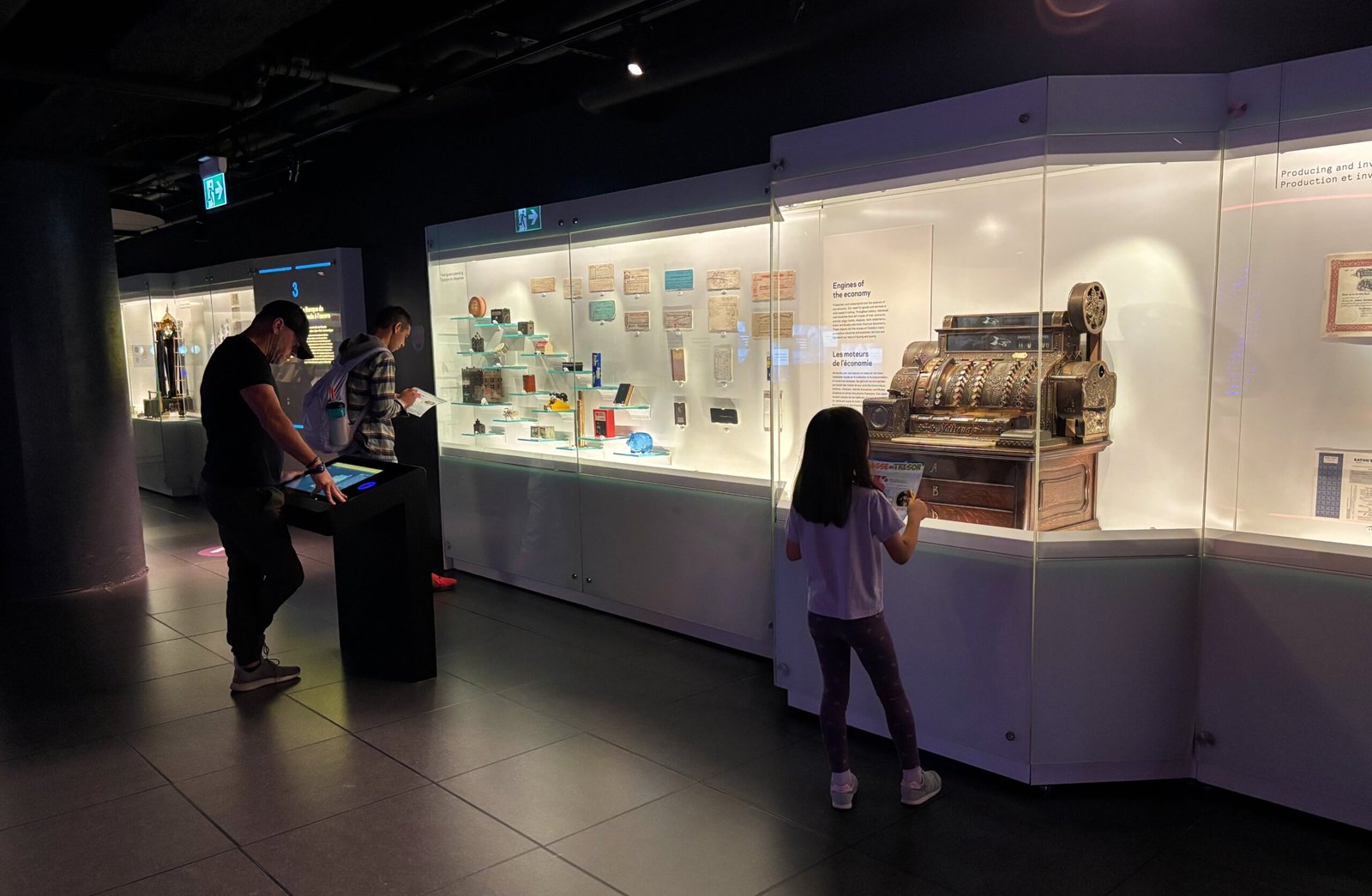 Visitors exploring an interactive touchscreen map of Canada inside the Bank of Canada Museum.