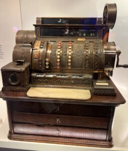 Display cases at the Bank of Canada Museum showing historic banking tools, coins, and an antique cash register.
