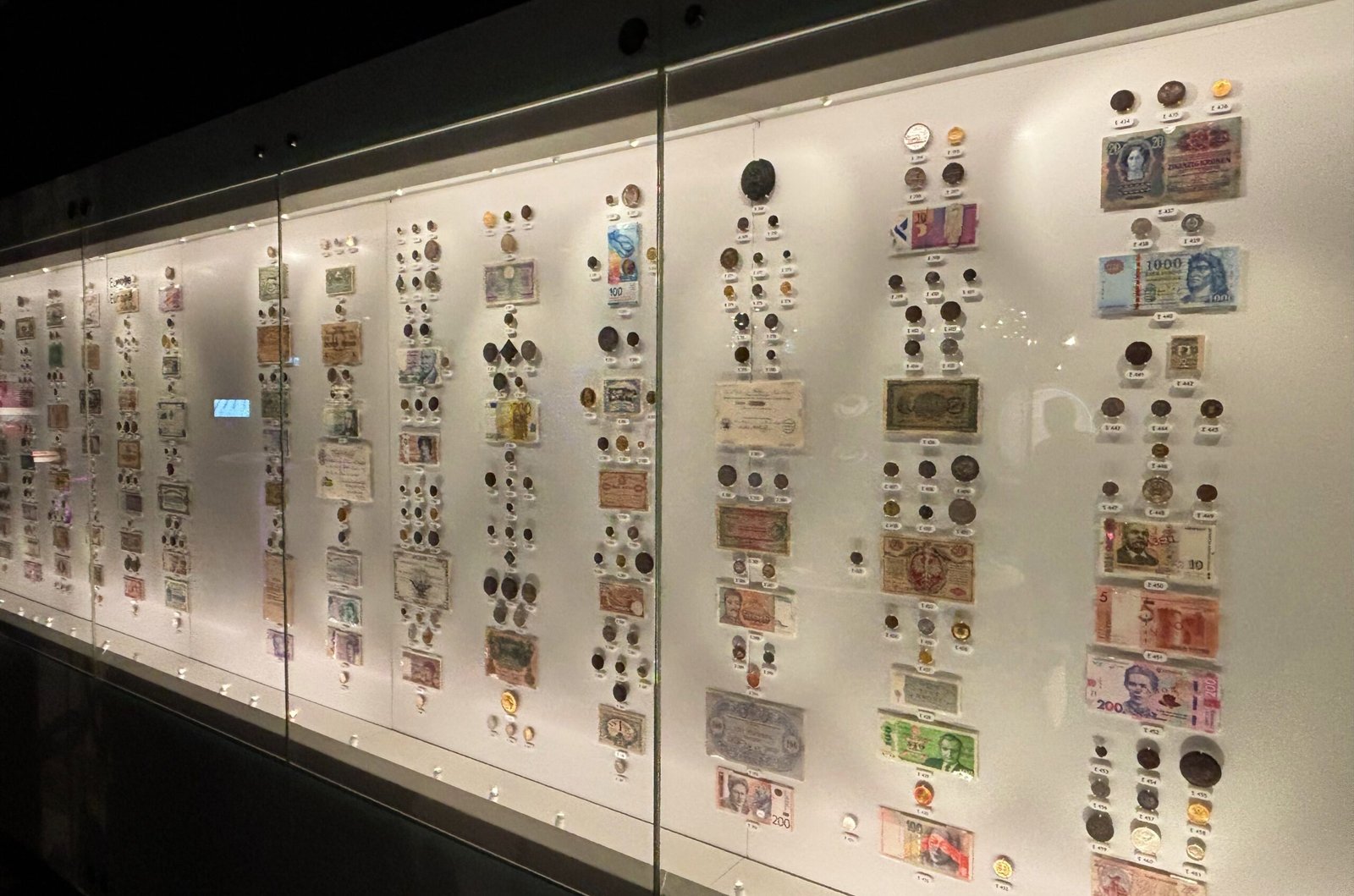 Wall display of world currencies with coins and banknotes from different countries at the Bank of Canada Museum.
