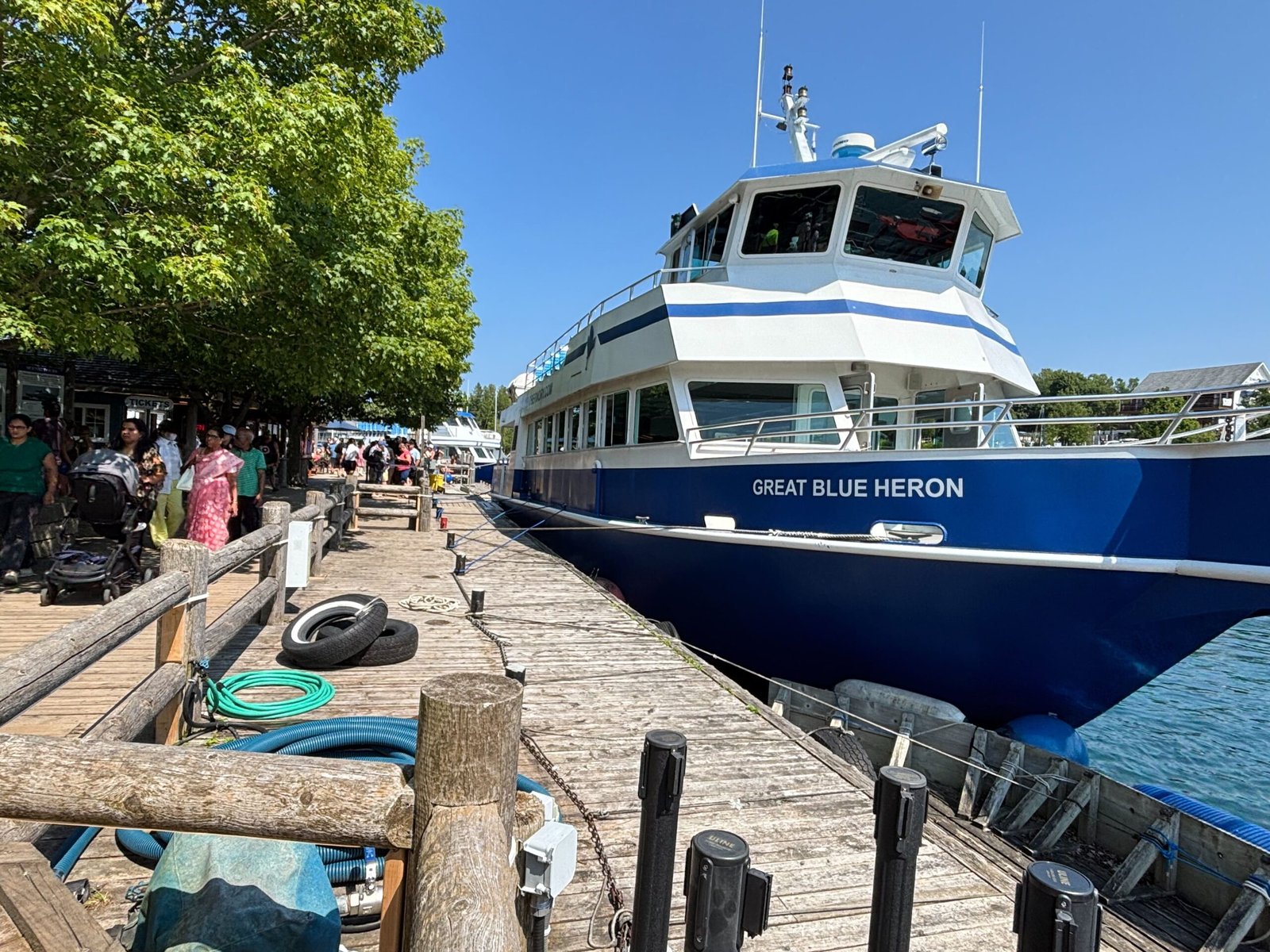 Great Blue Heron sightseeing boat docked at Tobermory harbour with visitors walking along the wooden pier.