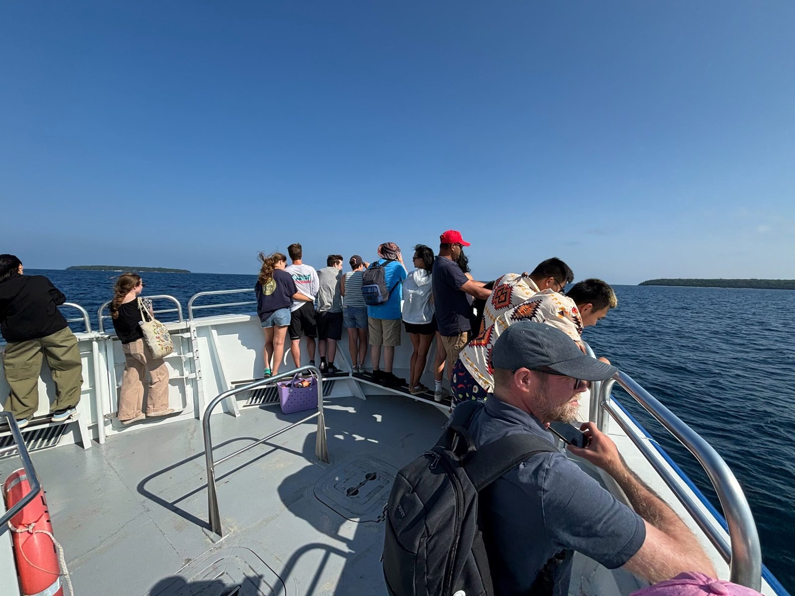 Passengers standing at the bow of the Blue Heron boat, looking out over the blue waters of Georgian Bay.