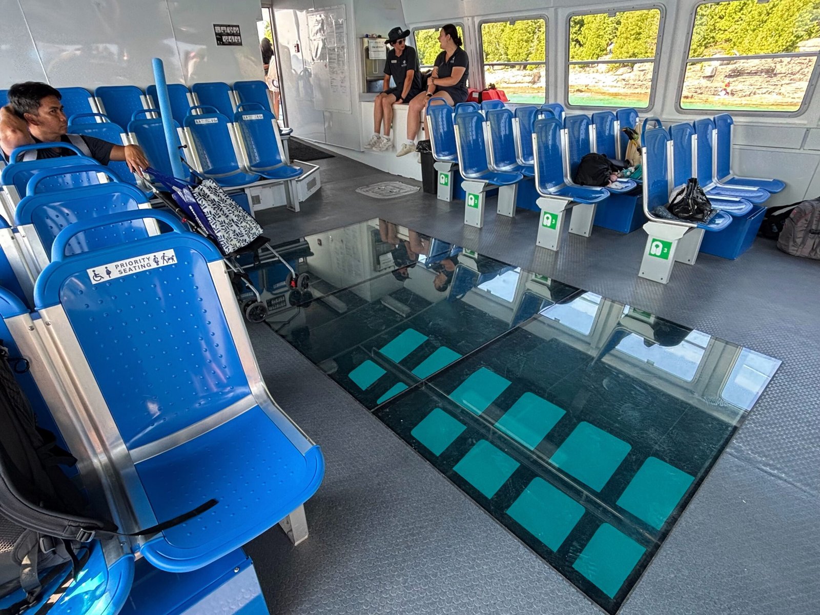Interior seating area of the Blue Heron boat with rows of blue chairs and glass-bottom viewing panels in the center.