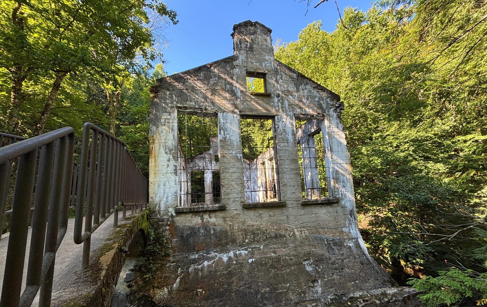 Front facade of Carbide Willson Ruins in Gatineau Park, with large window openings and surrounding trees.