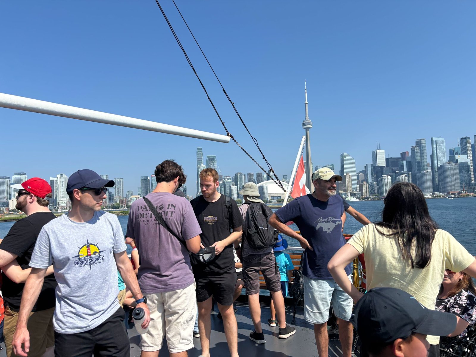 Passengers standing on the upper deck of the Oriole with Toronto skyline in the background.