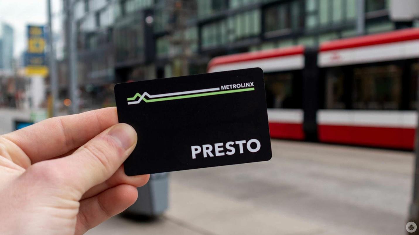Person holding a presto card in the streets of toronto with a streetcar in background