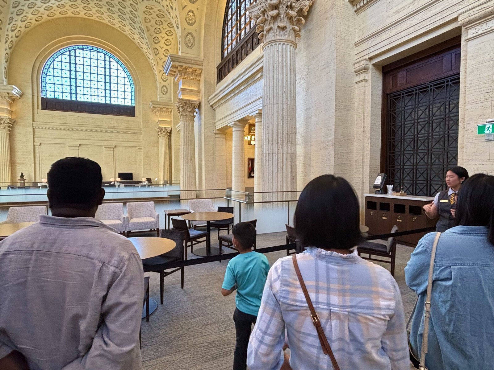 Visitors with a guide inside the Senate foyer near tall arched windows.