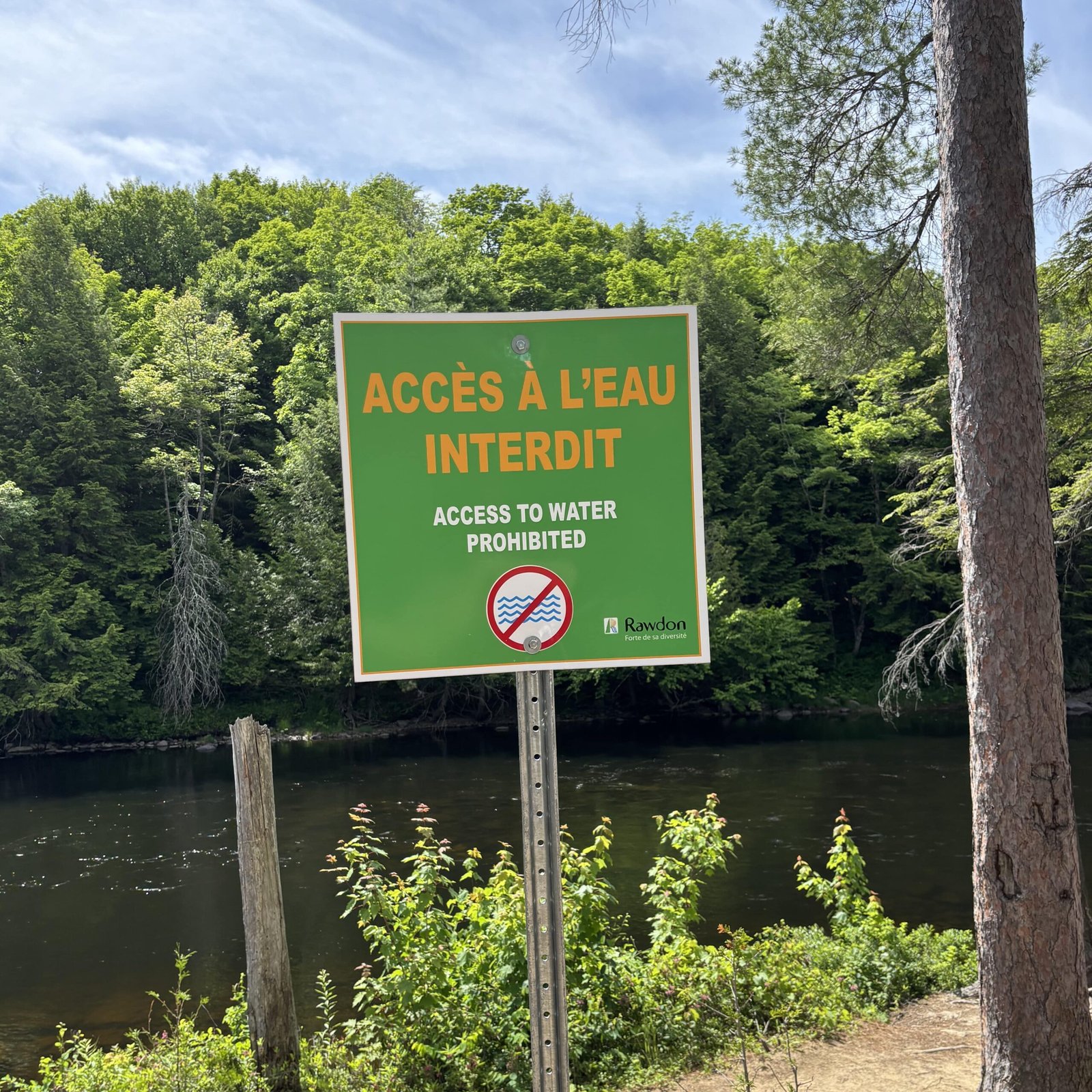 Green sign near the river warning that access to water is prohibited at Dorwin Falls.