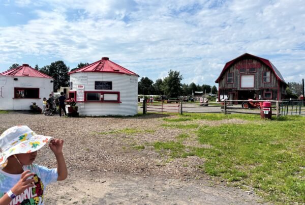 Two snack stands and the Quinn Farm barn in the distance, with visitors walking around.