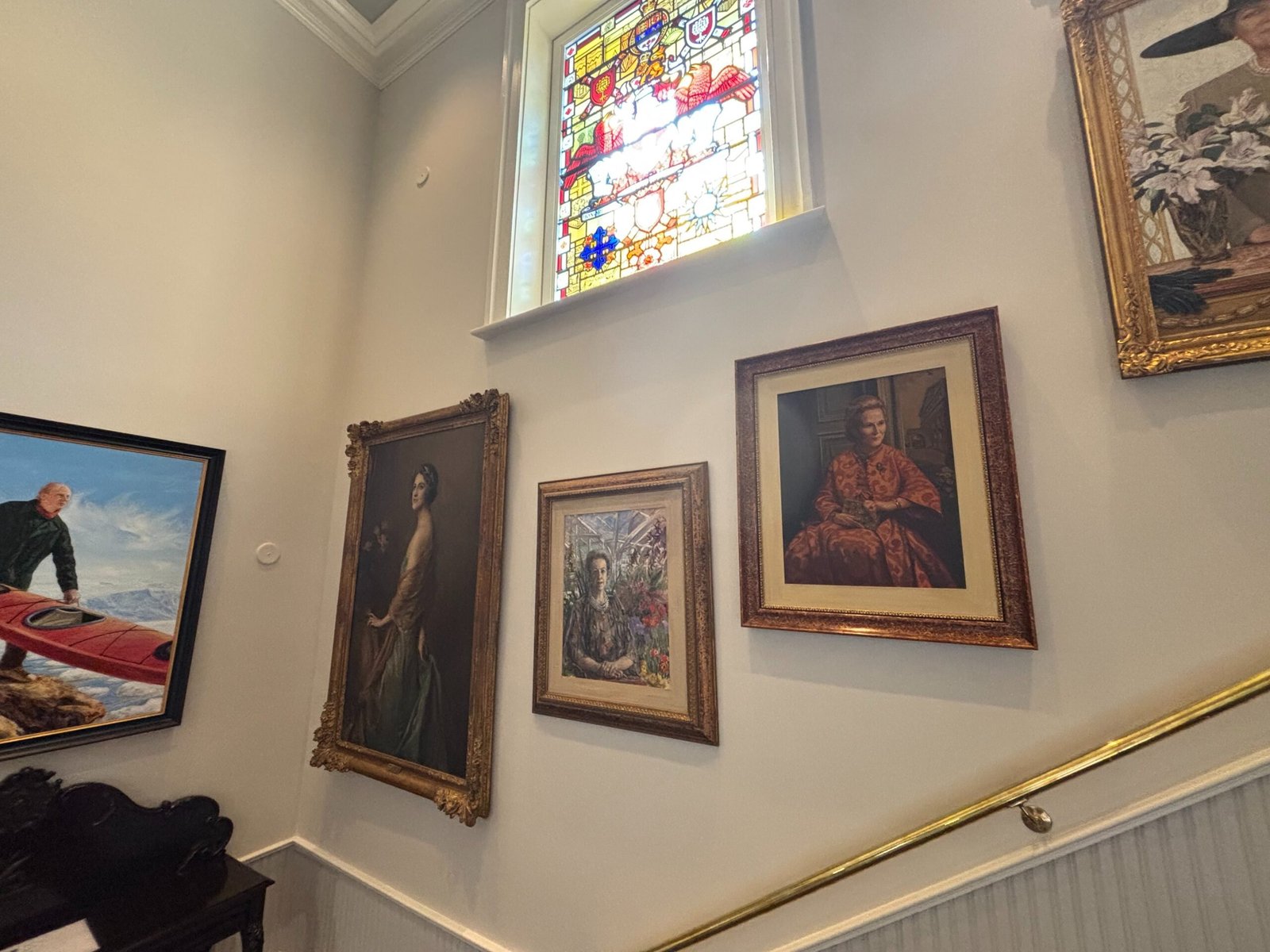 Wall of portraits and stained glass window inside Rideau Hall