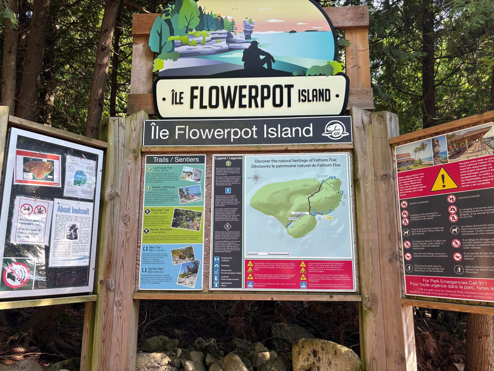 Entrance signboard at Flowerpot Island showing trail maps, park rules, and visitor information in English and French.