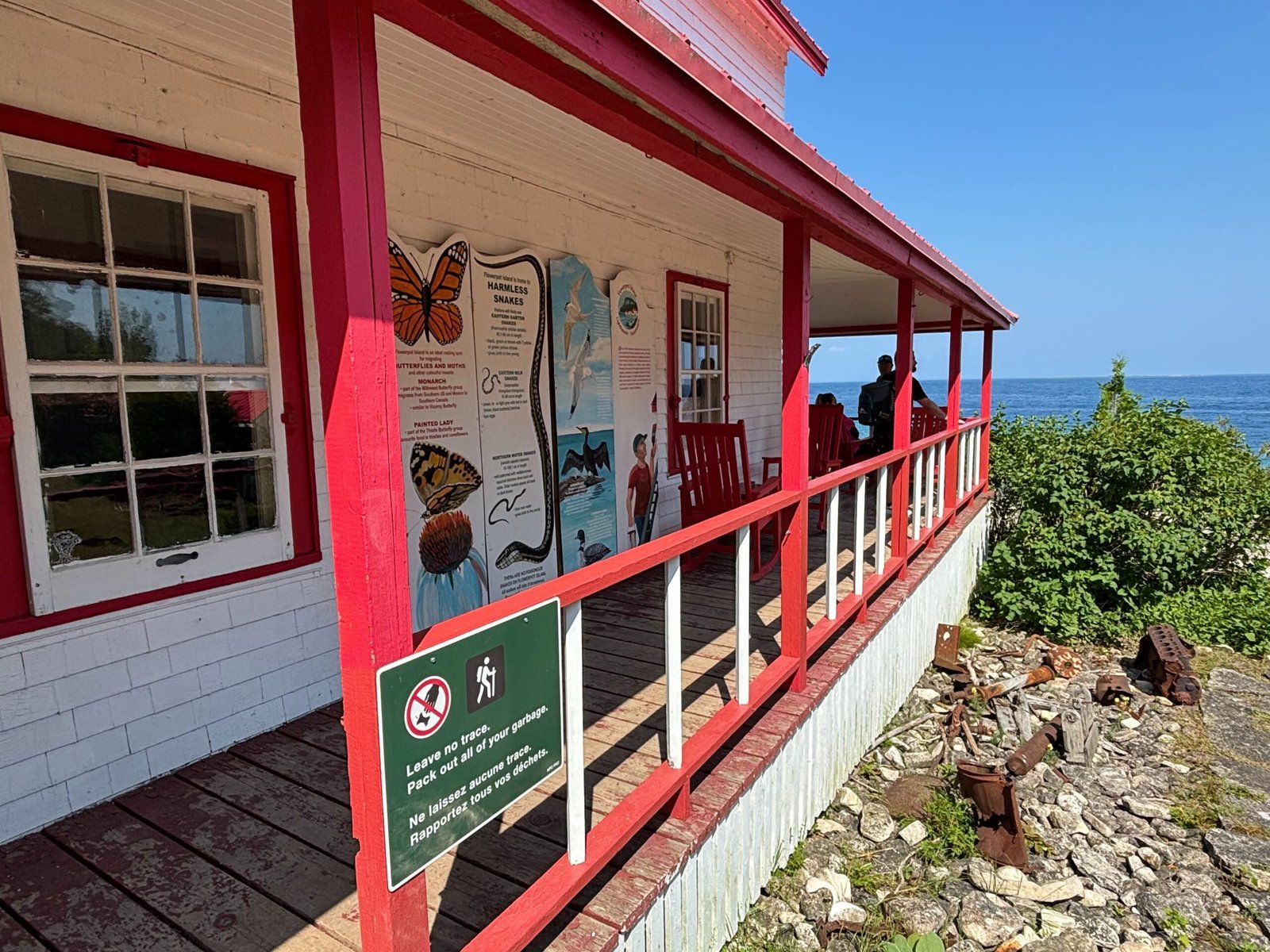 Red-and-white wooden porch of the Lightstation, with educational signs about local wildlife and “Leave no trace” notice.