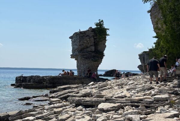 View of the second Flowerpot sea stack with people relaxing and exploring the rocky beach.