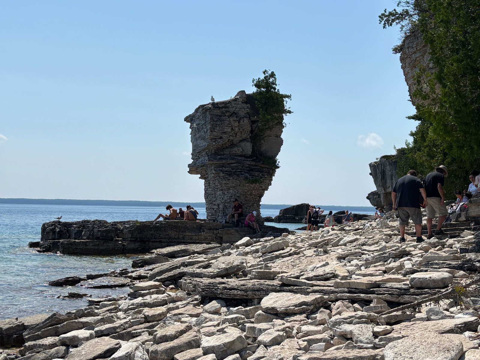 View of the second Flowerpot sea stack with people relaxing and exploring the rocky beach.
