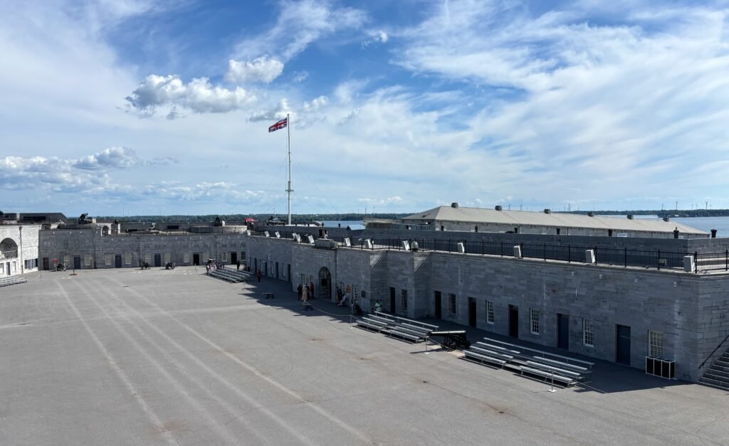 Wide view of Fort Henry’s courtyard with Union Jack flag flying above the ramparts.