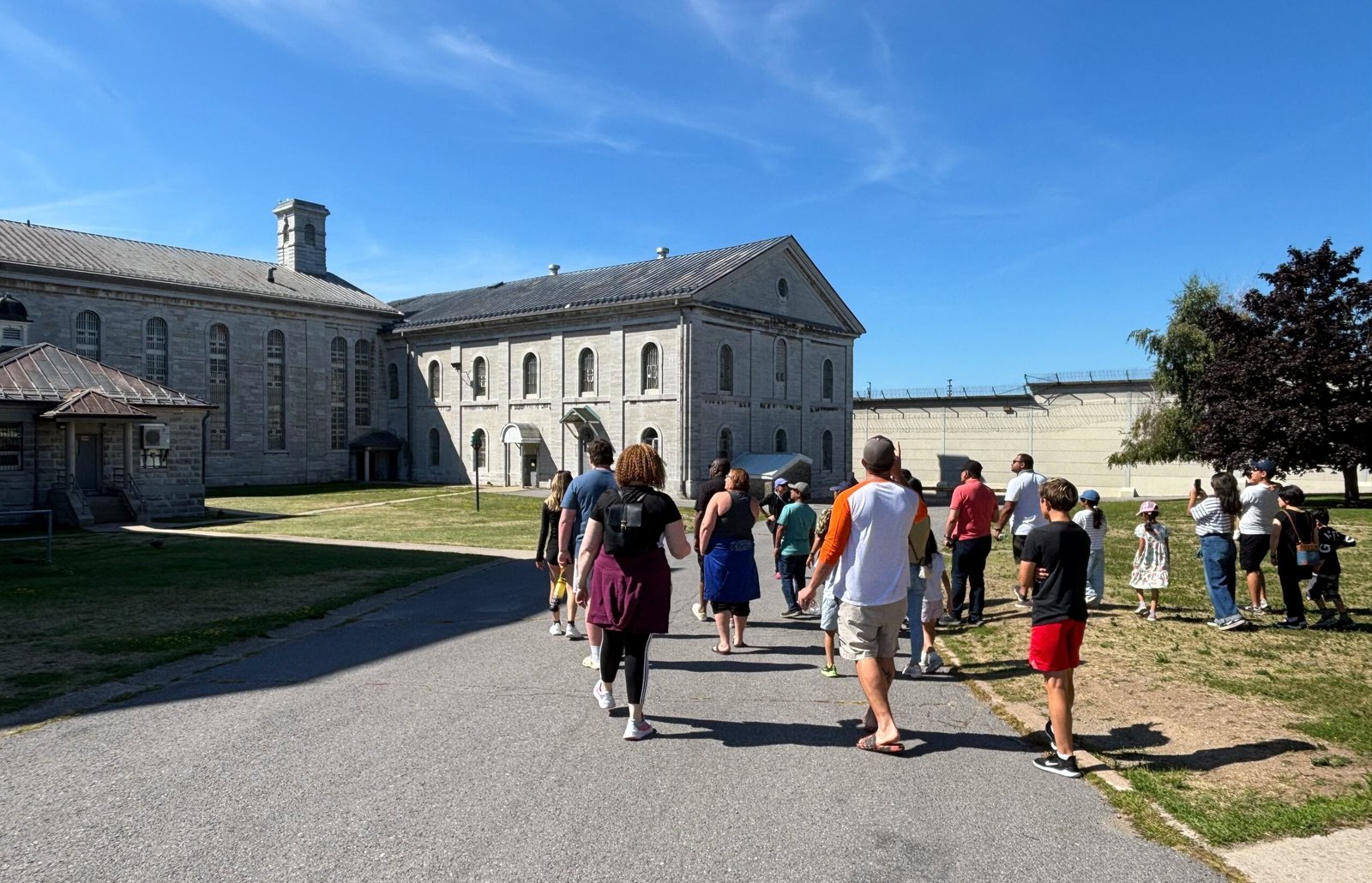 Tour group walking across the prison yard toward Kingston Penitentiary’s tour main buildings.