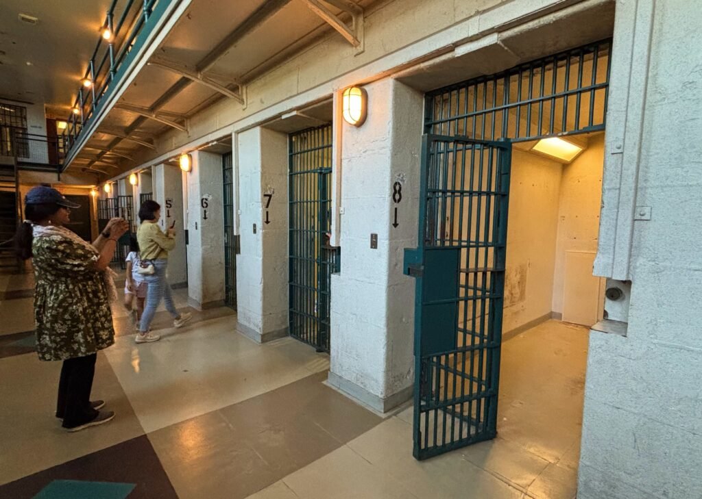 Row of numbered prison cells with doors open inside Kingston Penitentiary.