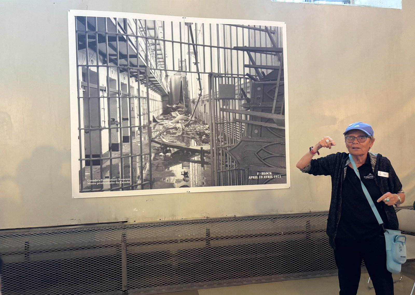 Tour guide speaking in front of a historic photo of a 1971 prison riot at Kingston Penitentiary.