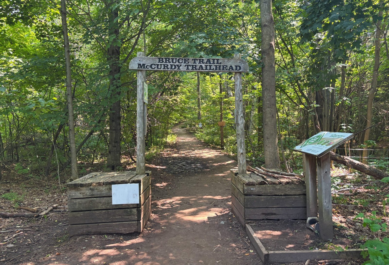 Wooden entry arch for the Bruce Trail McCurdy Trailhead at Lion’s Head, with a forest path stretching into the trees.