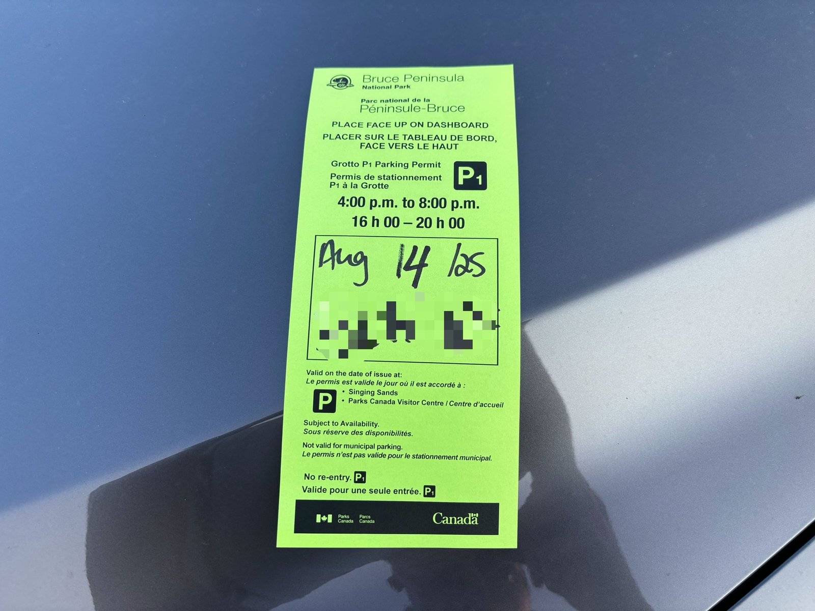 Parks Canada parking permit for the Grotto in Bruce Peninsula National Park placed on a car dashboard.