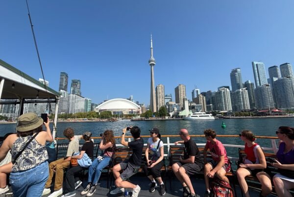 Tourists on the Oriole boat taking photos of Toronto’s skyline and CN Tower.