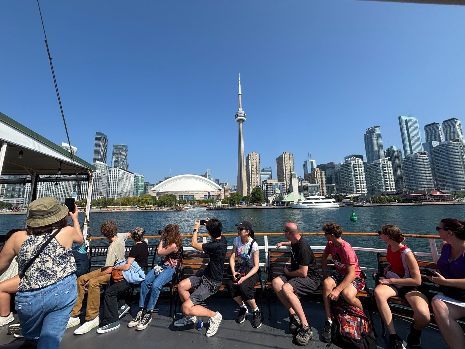 Tourists on the Oriole boat taking photos of Toronto’s skyline and CN Tower.